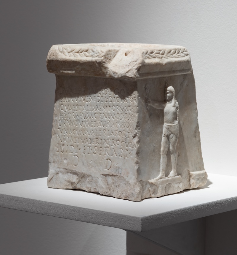 An ancient marble votive altar on a pedestal.