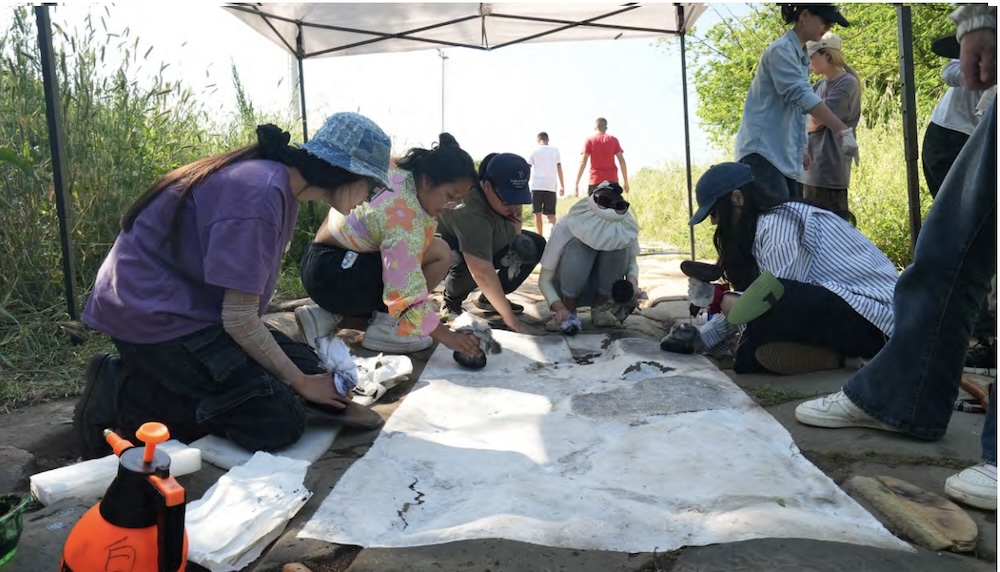 People work collaboratively on a rubbing of the Appian Way