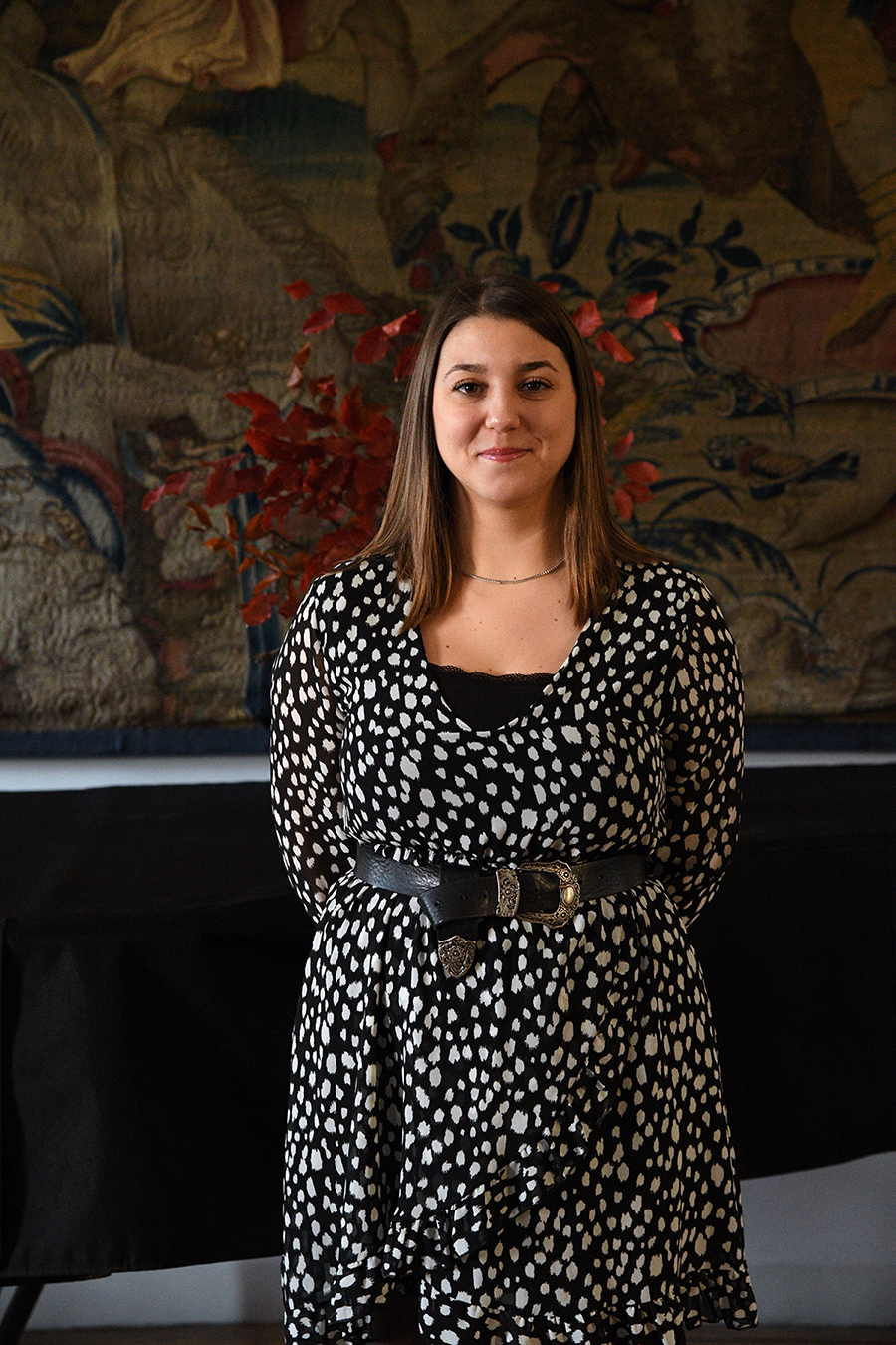 Color photo of a light skinned woman wearing a black and white spotted dress