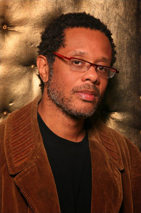Don Byron Color photograph of the head and torso of a dark skinned man wearing glasses and a brown corduroy blazer