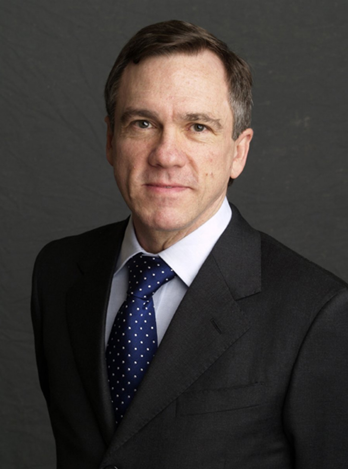 Gregory Waldrop color Color photograph of the head and torso of a light skinned man wearing glasses and a dark suit and tie