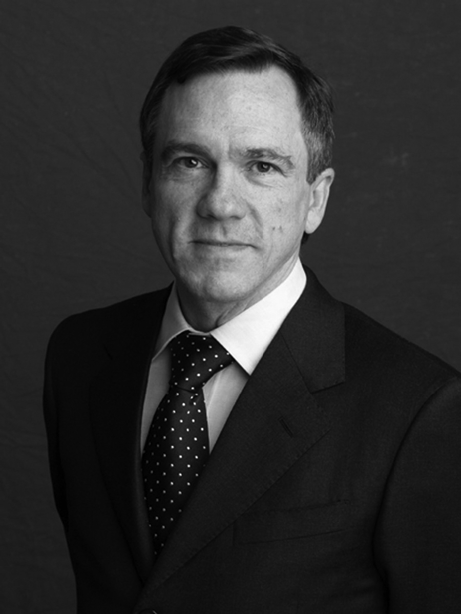 Gregory Waldrop Black and white photograph of the head and torso of a light skinned man wearing glasses and a dark suit and tie