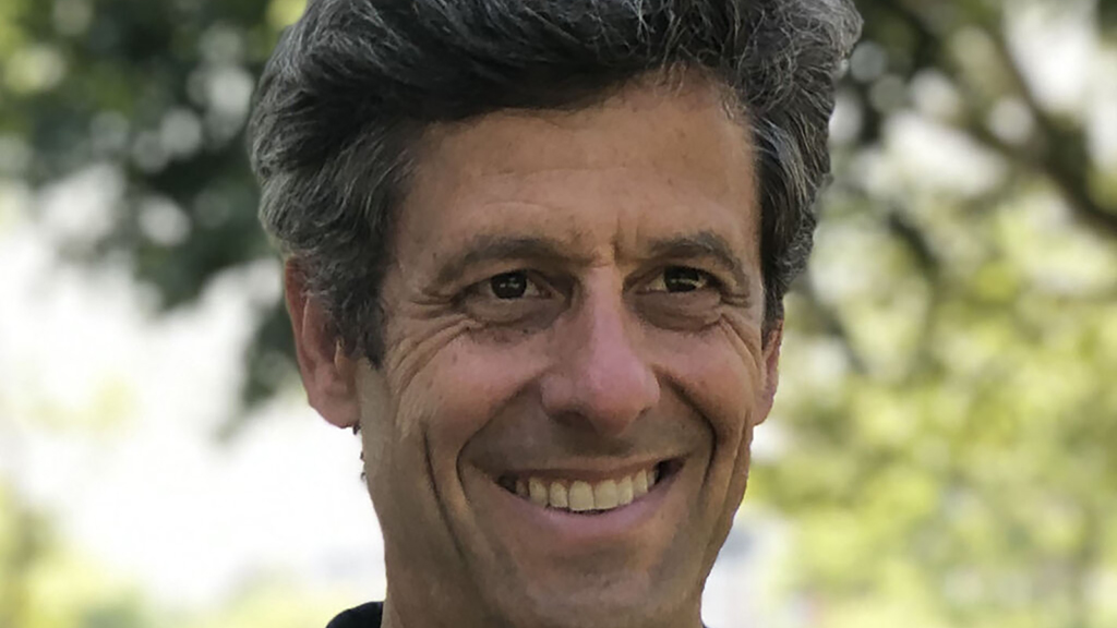 Color photograph of the face of David Karmon standing outside underneath a tree