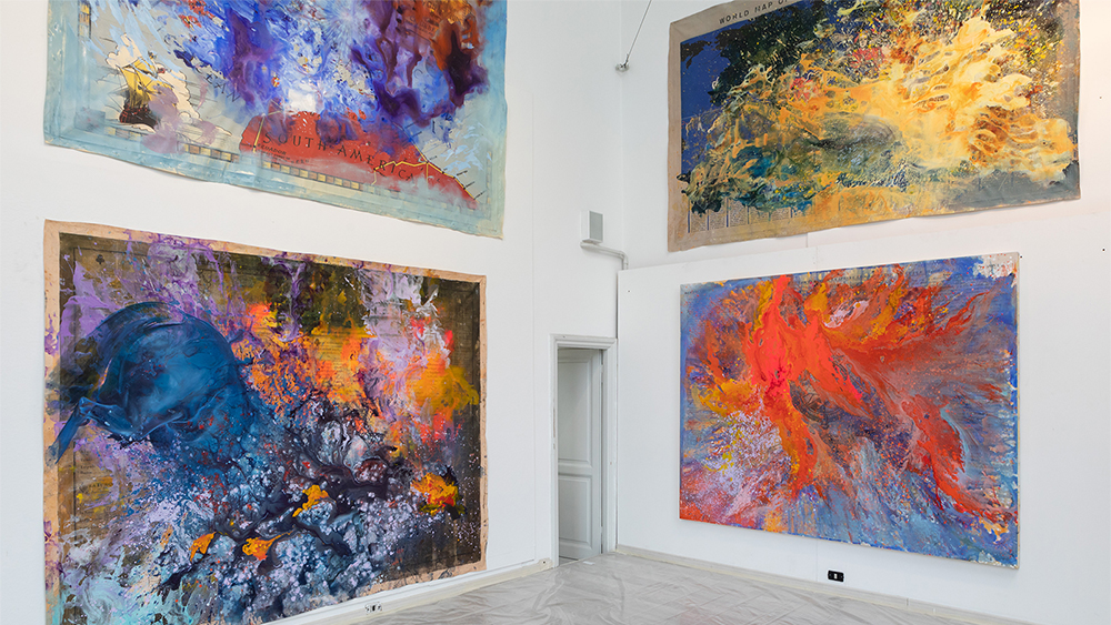 Color photo of an artist's studio with four large abstract paintings hung on adjacent walls