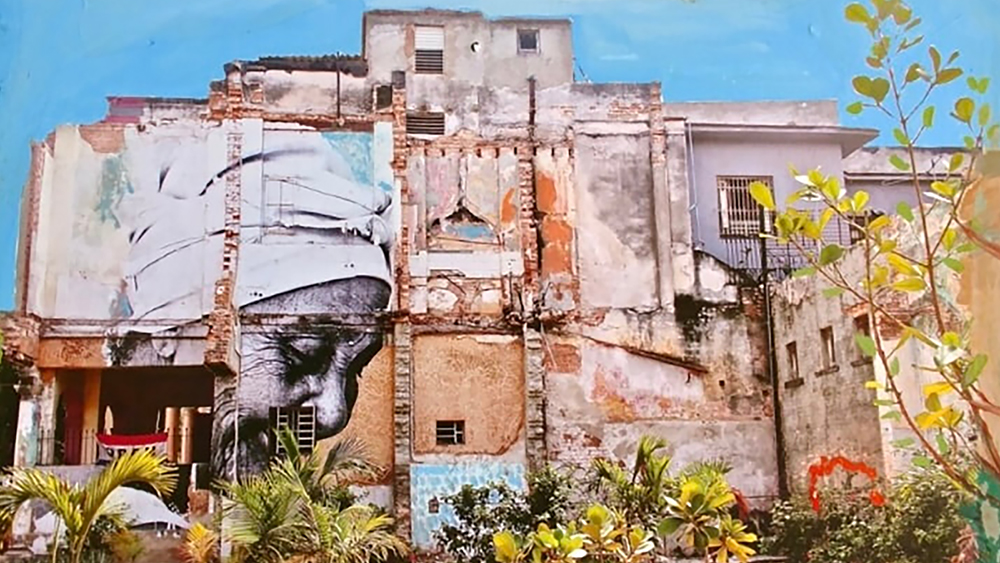 Detail of a collage artwork of photo and painting depicting the a mural of a woman's face on the side of a building