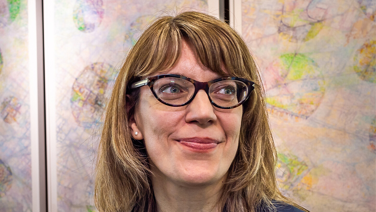 Color photo of the head of a light skinned woman wearing glasses and looking off camera