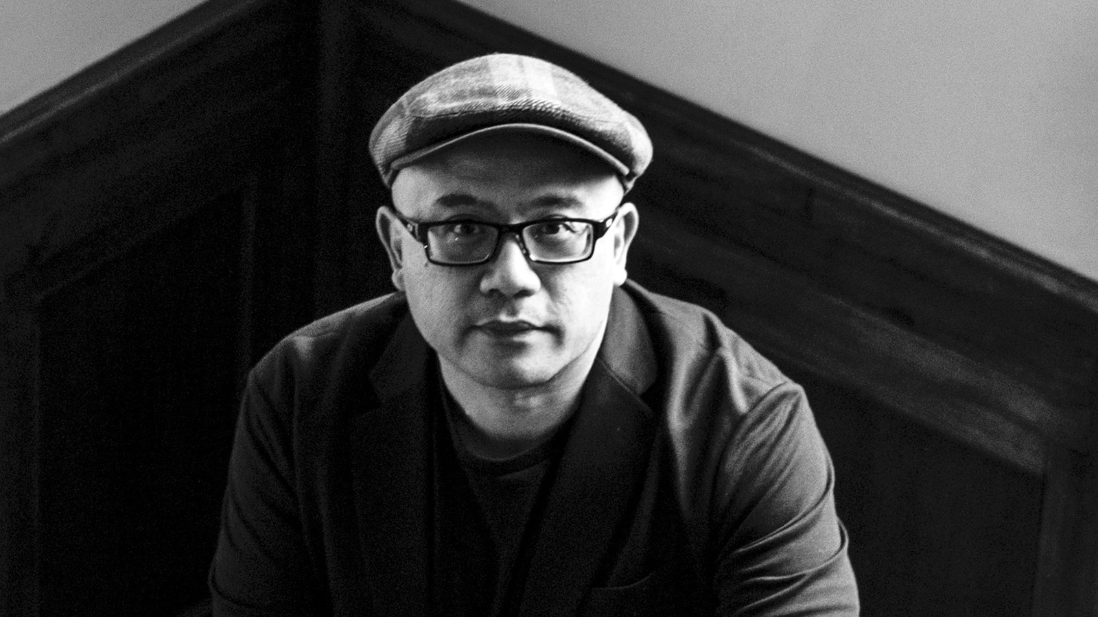 Black and white portrait of Lysley Tenorio in a wood-paneled stairway