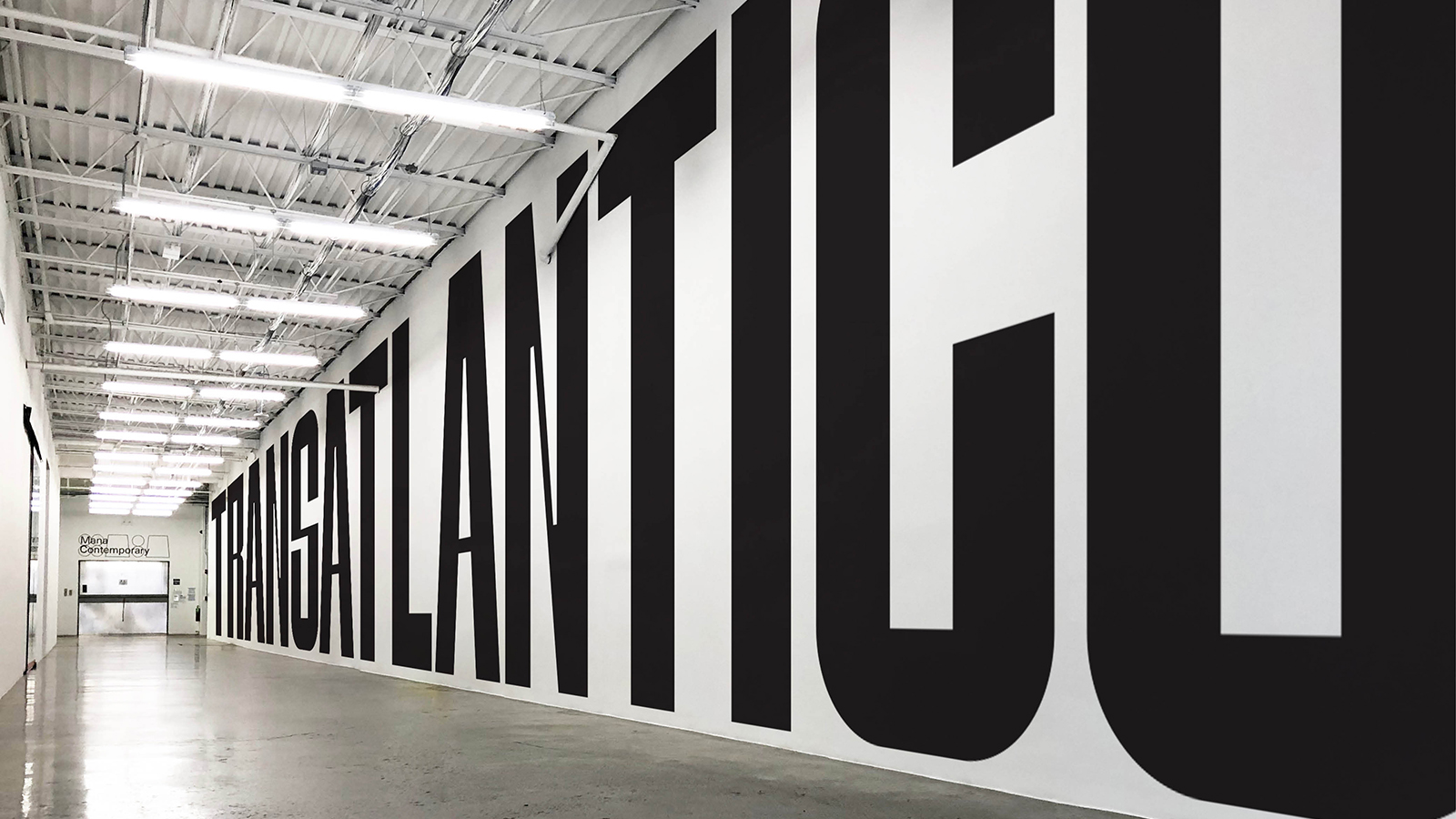 Color photograph of Mana Contemporary entrance hall with the word Transatlantico in large black letters on the wall