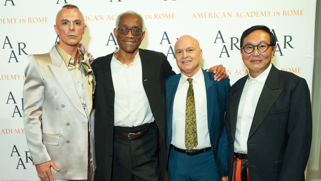 Four men of varying skin tones standing in front of a step and repeat