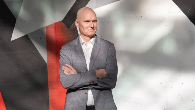 Color portrait of Anthony Doerr from head to hips, wearing a gray sportscoat and folding his arms