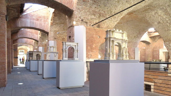 A color photograph of a museum installation of architectural models of ancient Roman buildings, each on a single plinth