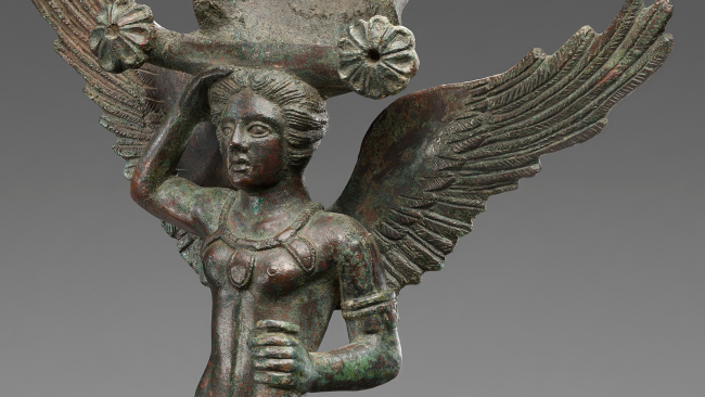 Color photograph of the head and torso of a figurative Etruscan statue of a winged man