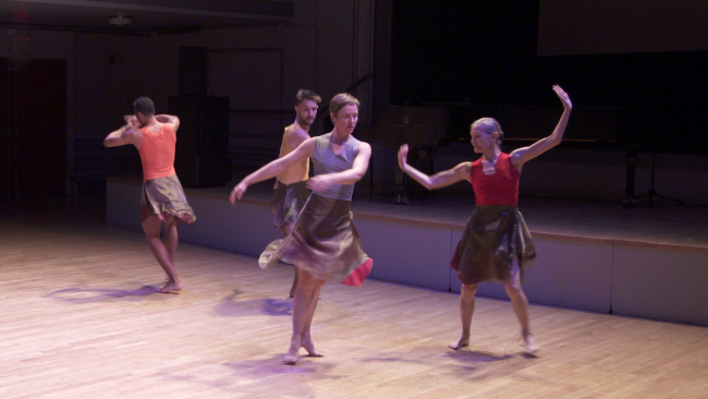 Color photo of four modern dancers (two men and woman) dancing in front of an unseen audience